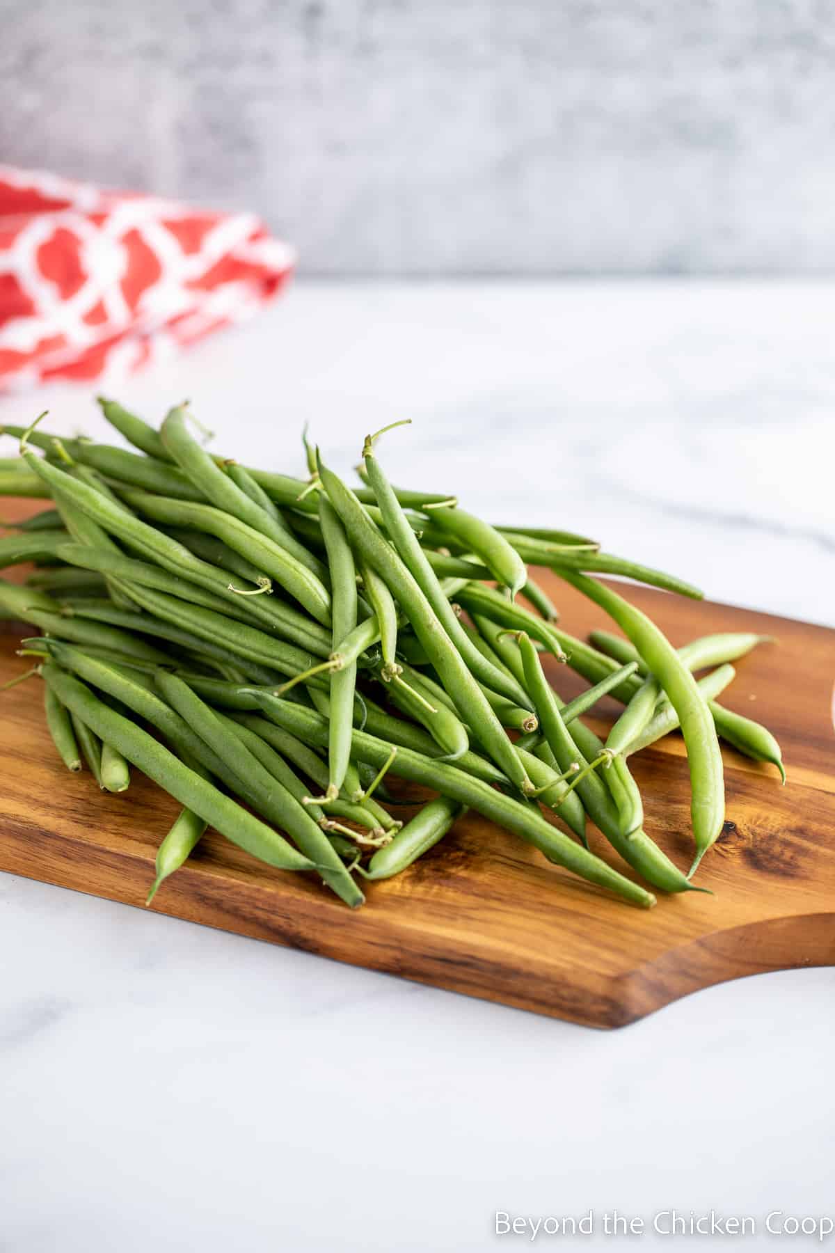 Fresh green beans on a wooden cutting board.