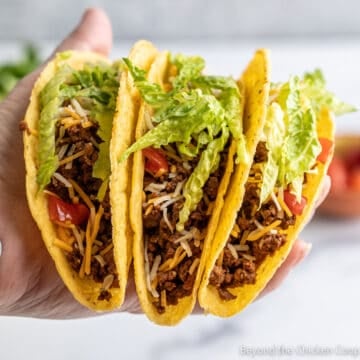 Three tacos held in a hand.