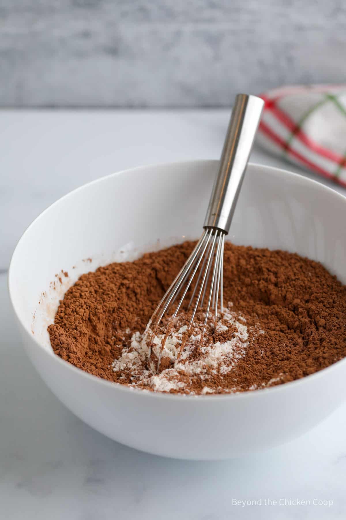 Mixing cocoa powder into a bowl of flour with a whisk.