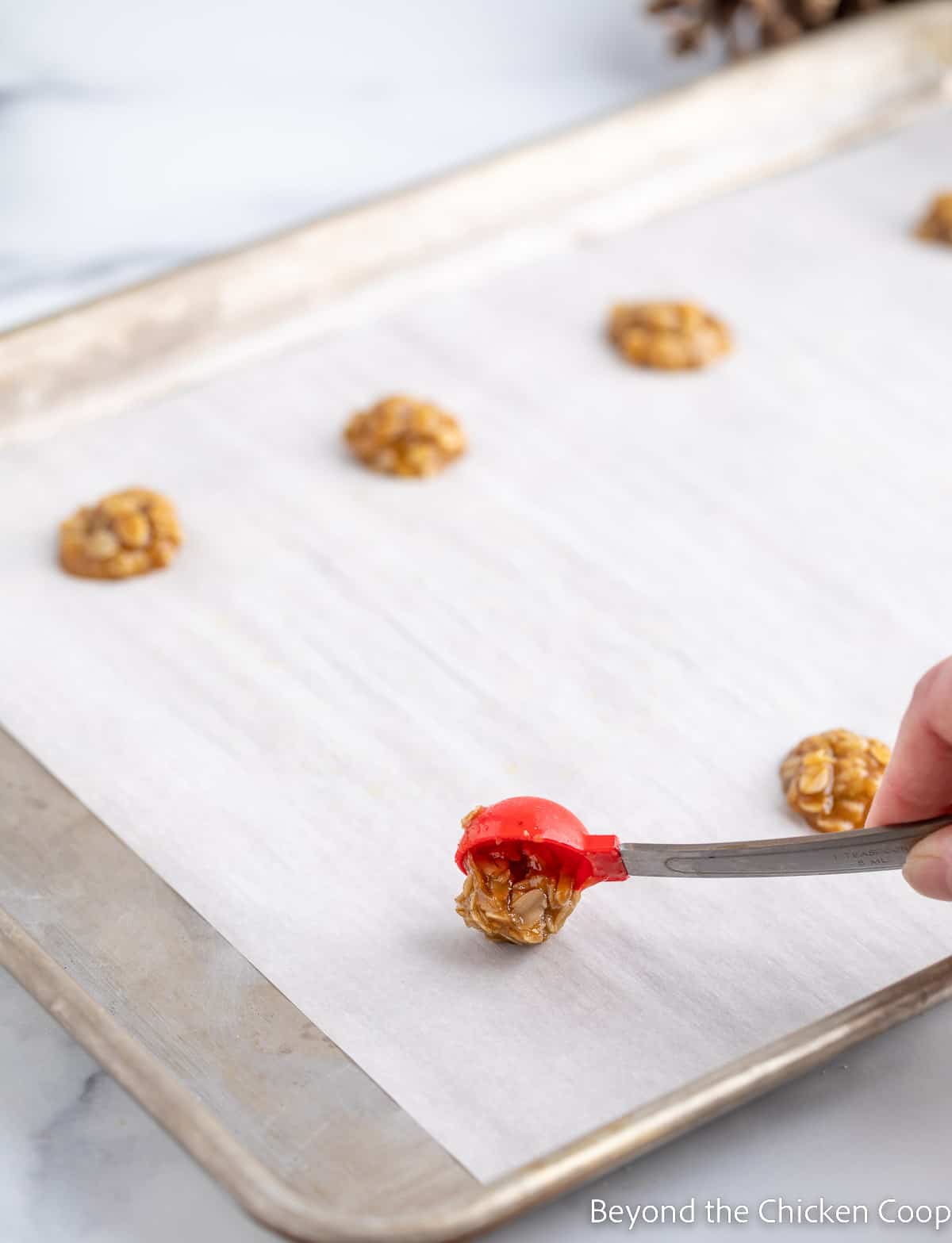 Measuring out one teaspoon of cookie batter onto a baking sheet.