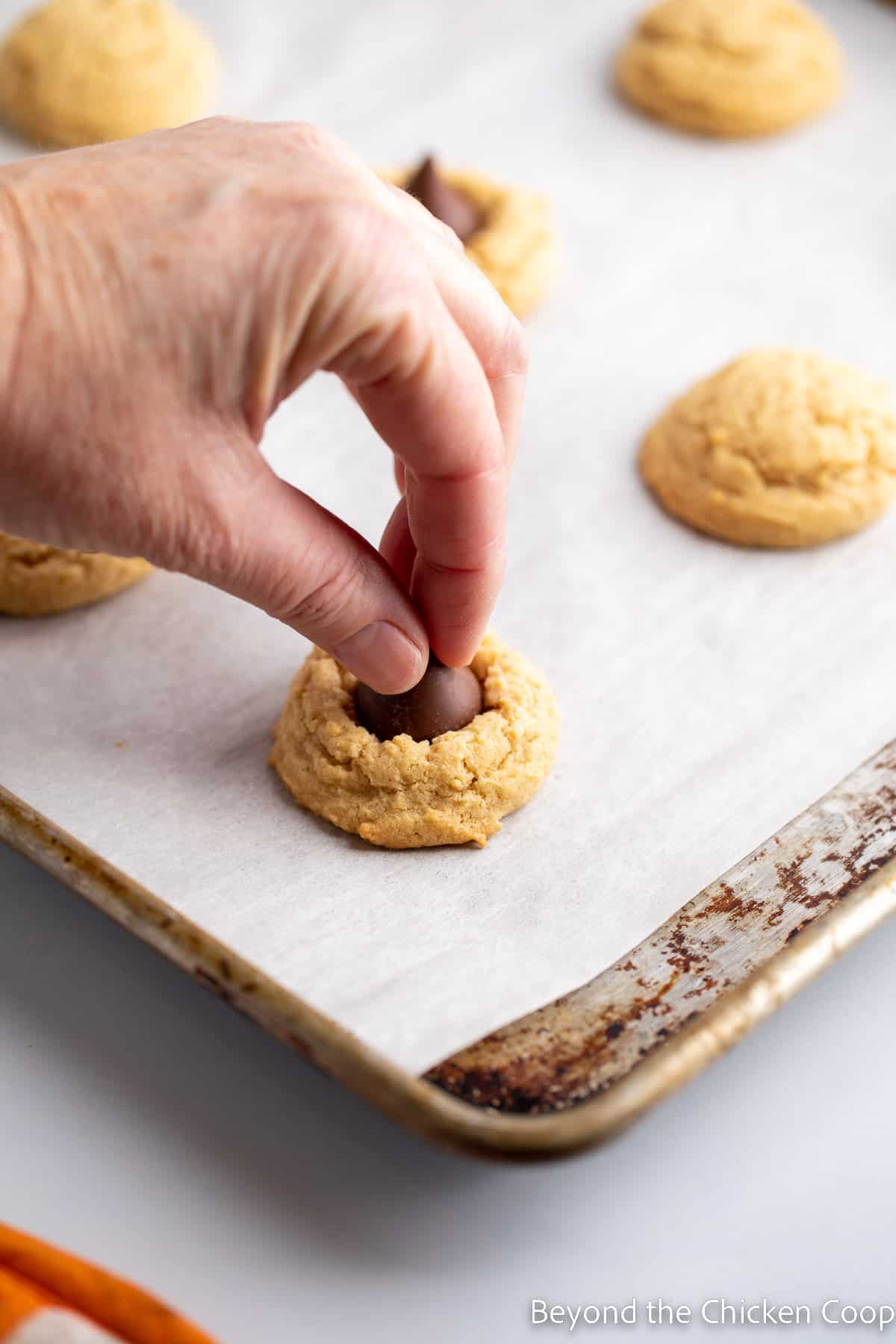 Placing a chocolate kiss on a cookie.