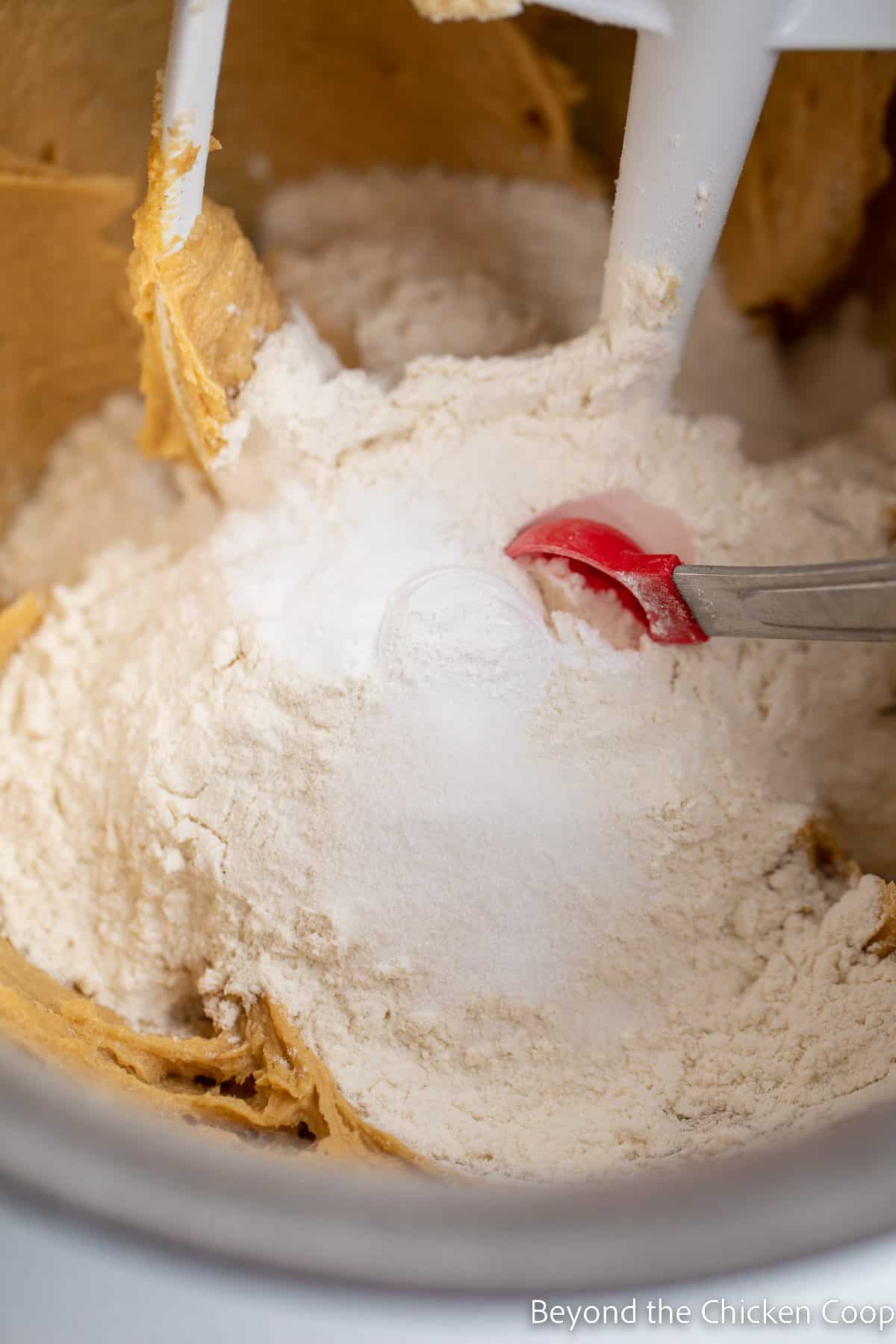 Flour added to a mixing bowl with cookie dough. 