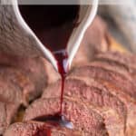A red wine sauce being poured over sliced meat.