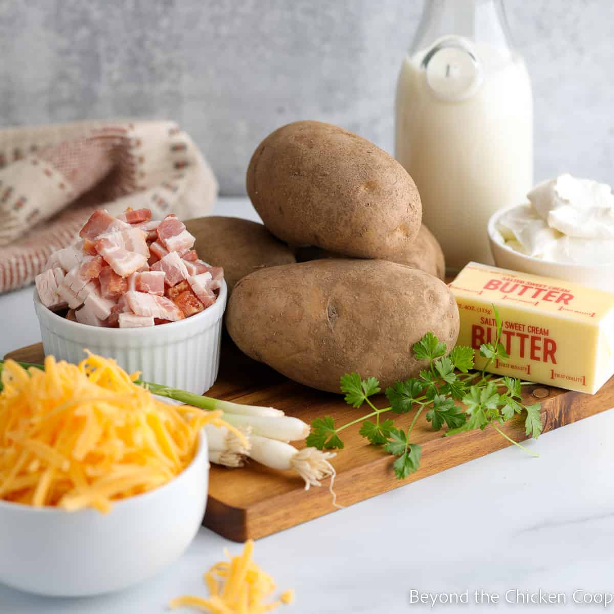 Potatoes, cheese, bacon and onions on a wooden cutting board. 