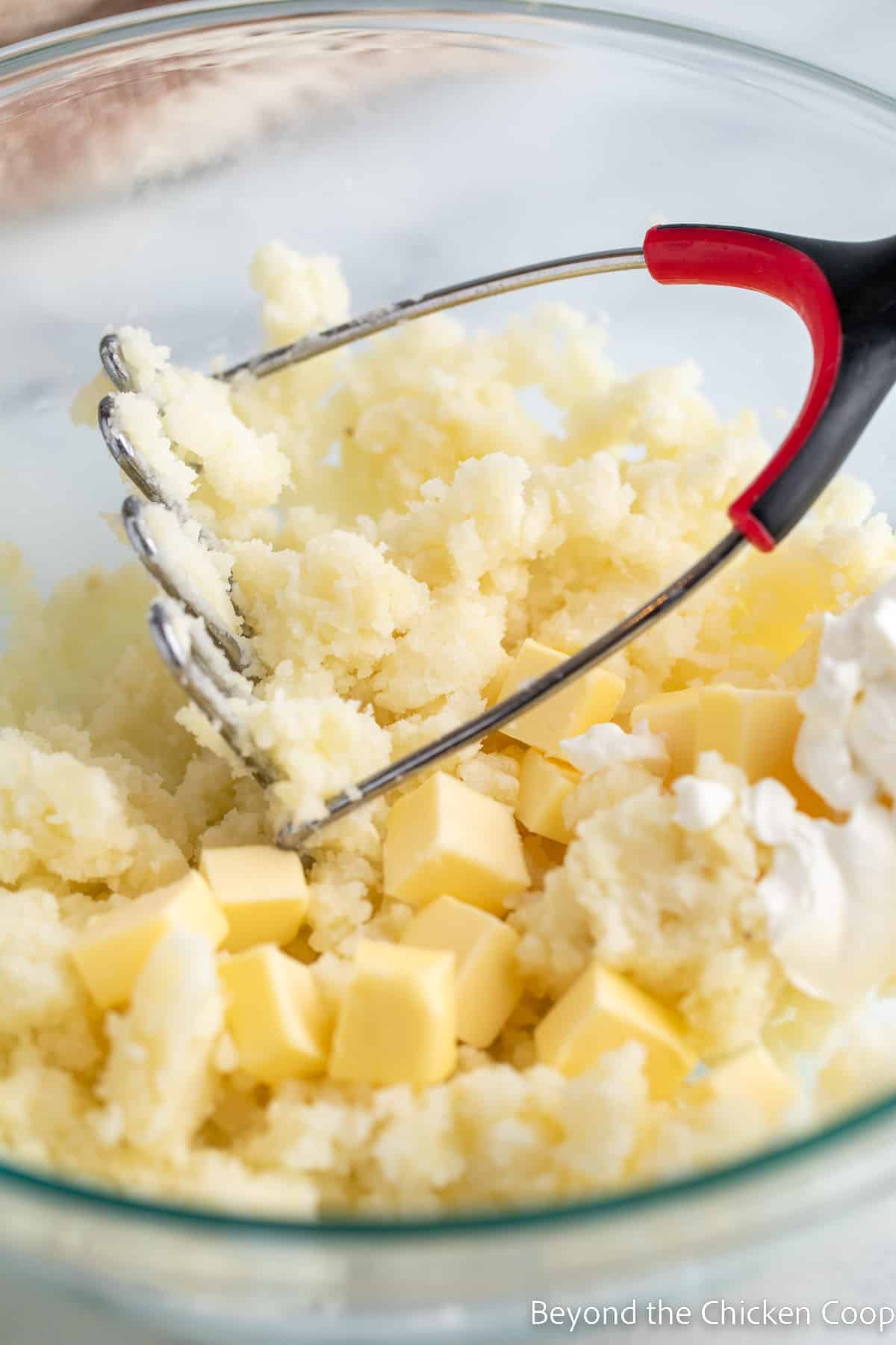 Mashed potatoes in a bowl with cubes of butter.