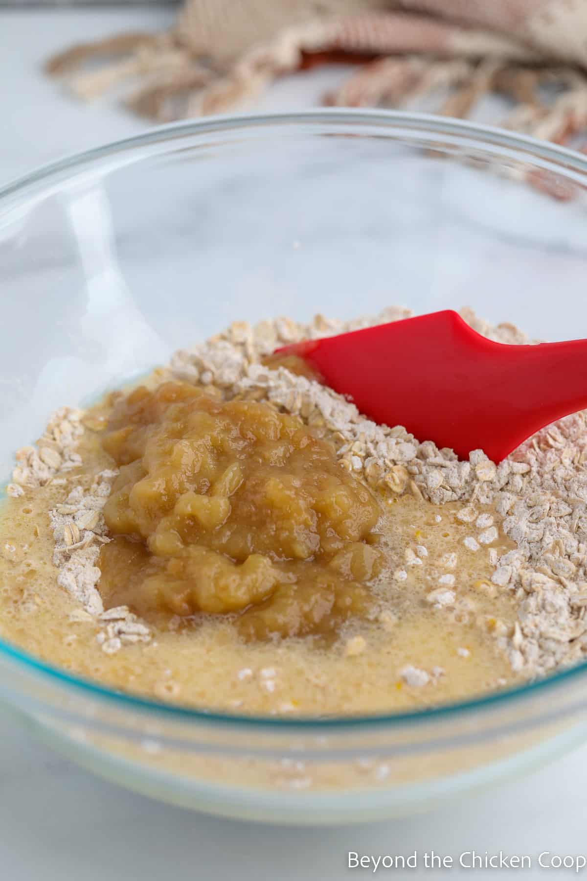 Combining a flour mixture with liquids and applesauce.