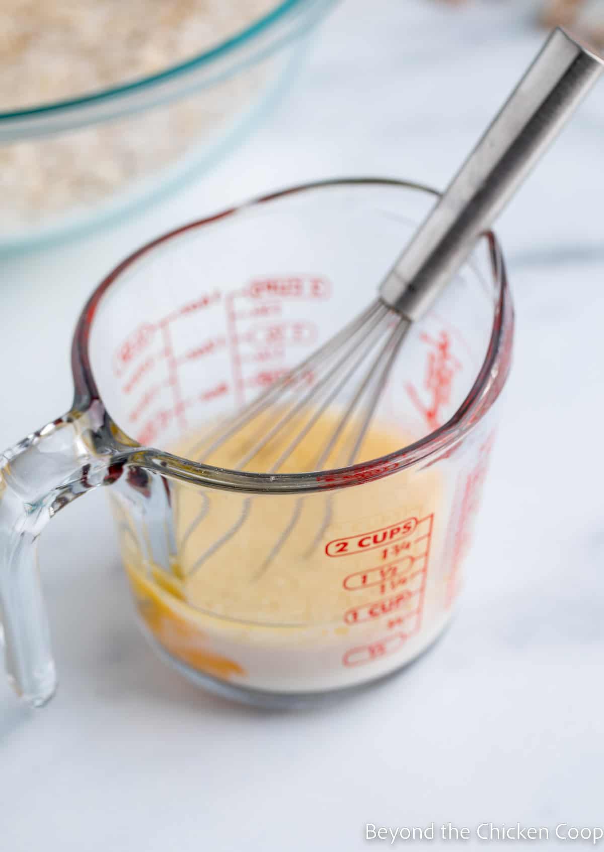 A glass measuring cup with milk and eggs. 