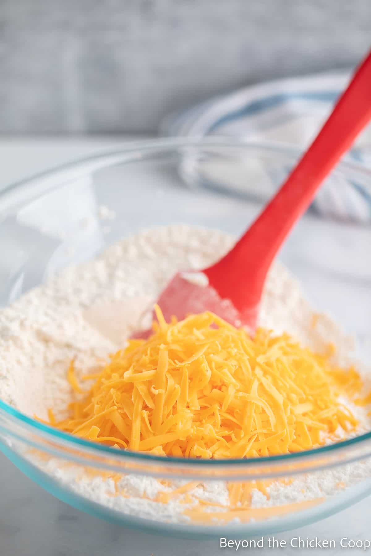 Shredded cheese in a bowl with flour. 