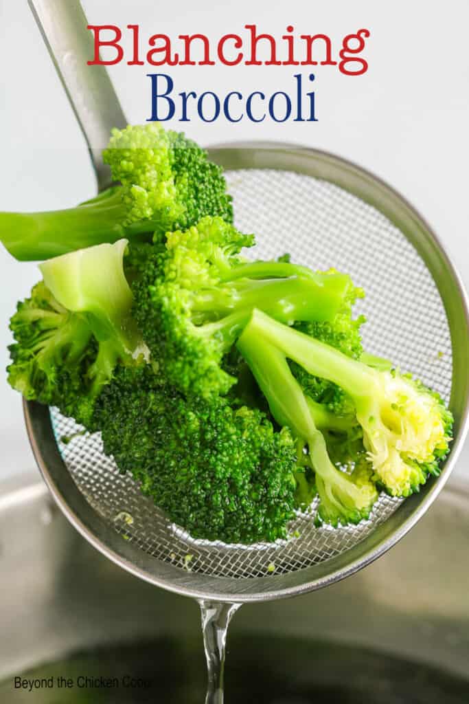 A skimmer filled with cooked broccoli.
