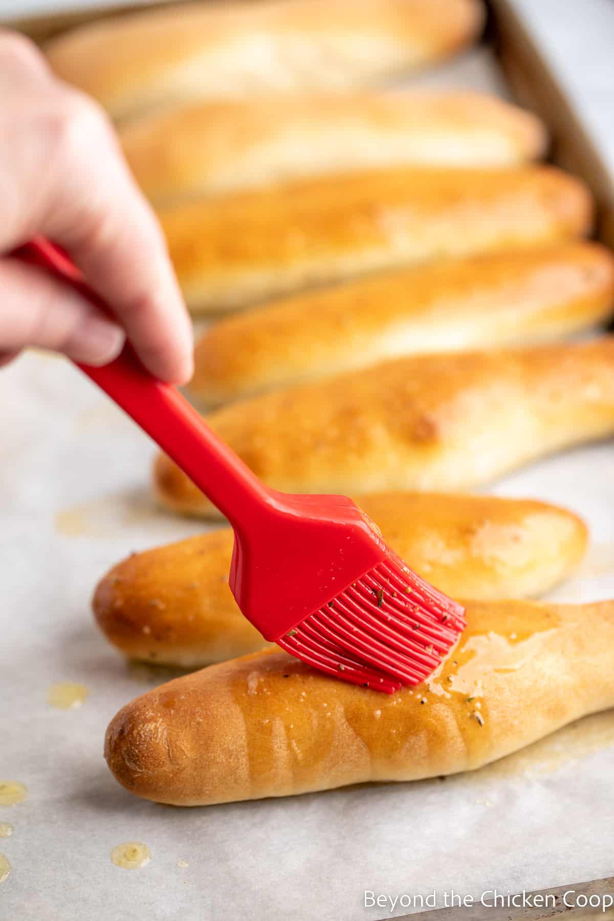 Brushing butter on breadsticks. 