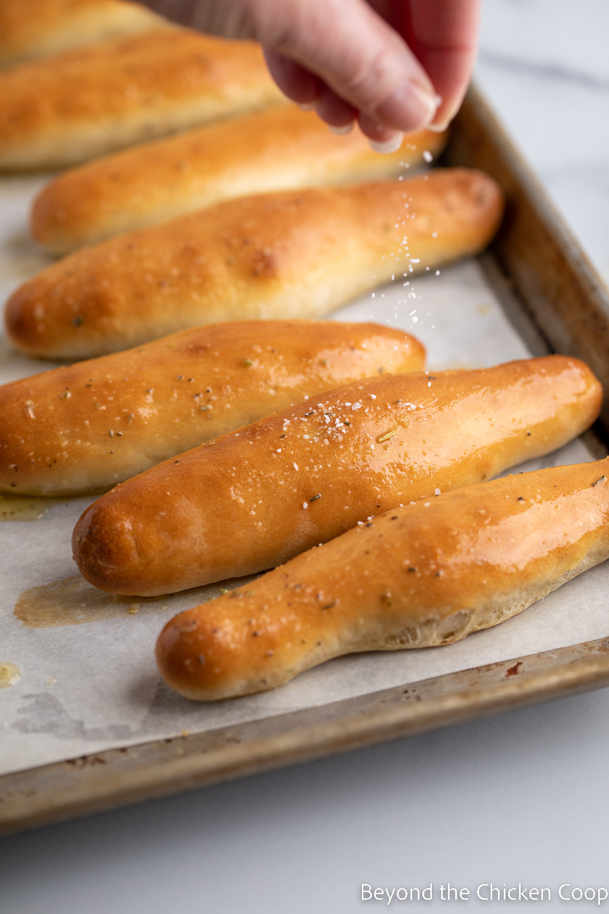 Sprinkling salt on breadsticks. 