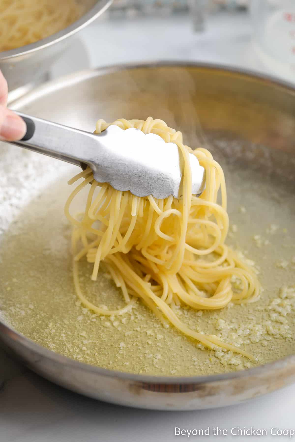 Adding spagetti noodles to a pan with butter.