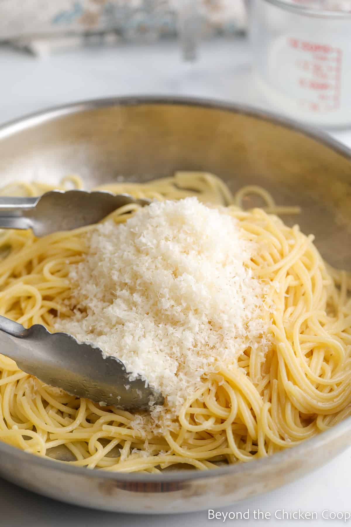 Shredded parmesan cheese on pasta in a pan. 