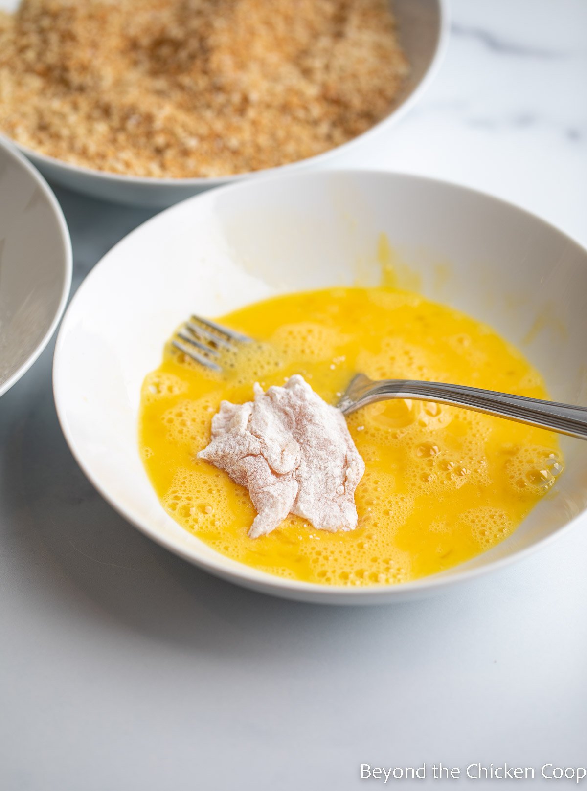 Dipping chicken into flour. 