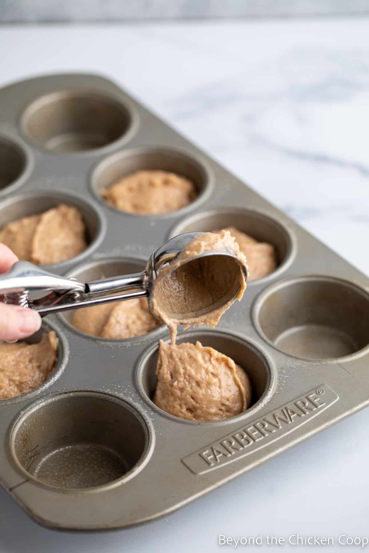 Scooping batter into a muffin tin. 