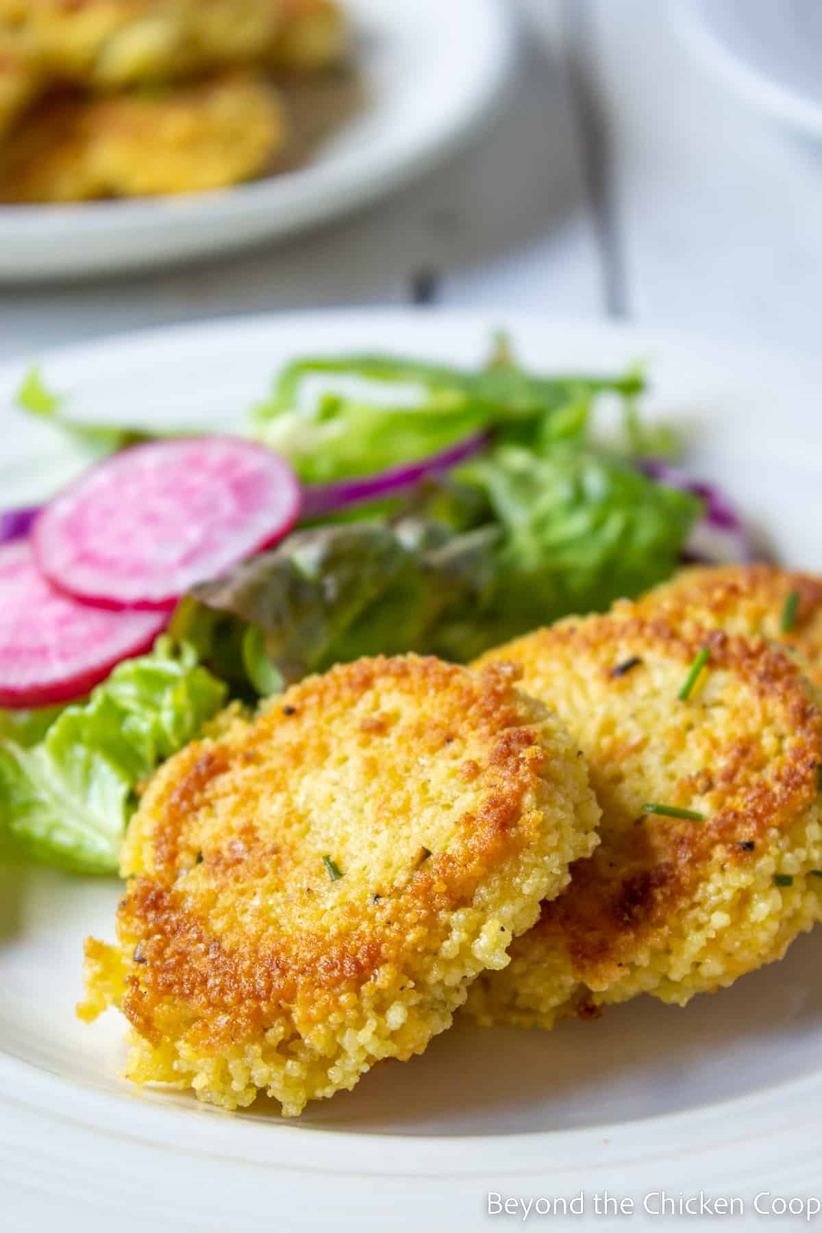 Couscous patties on a plate with a salad. 