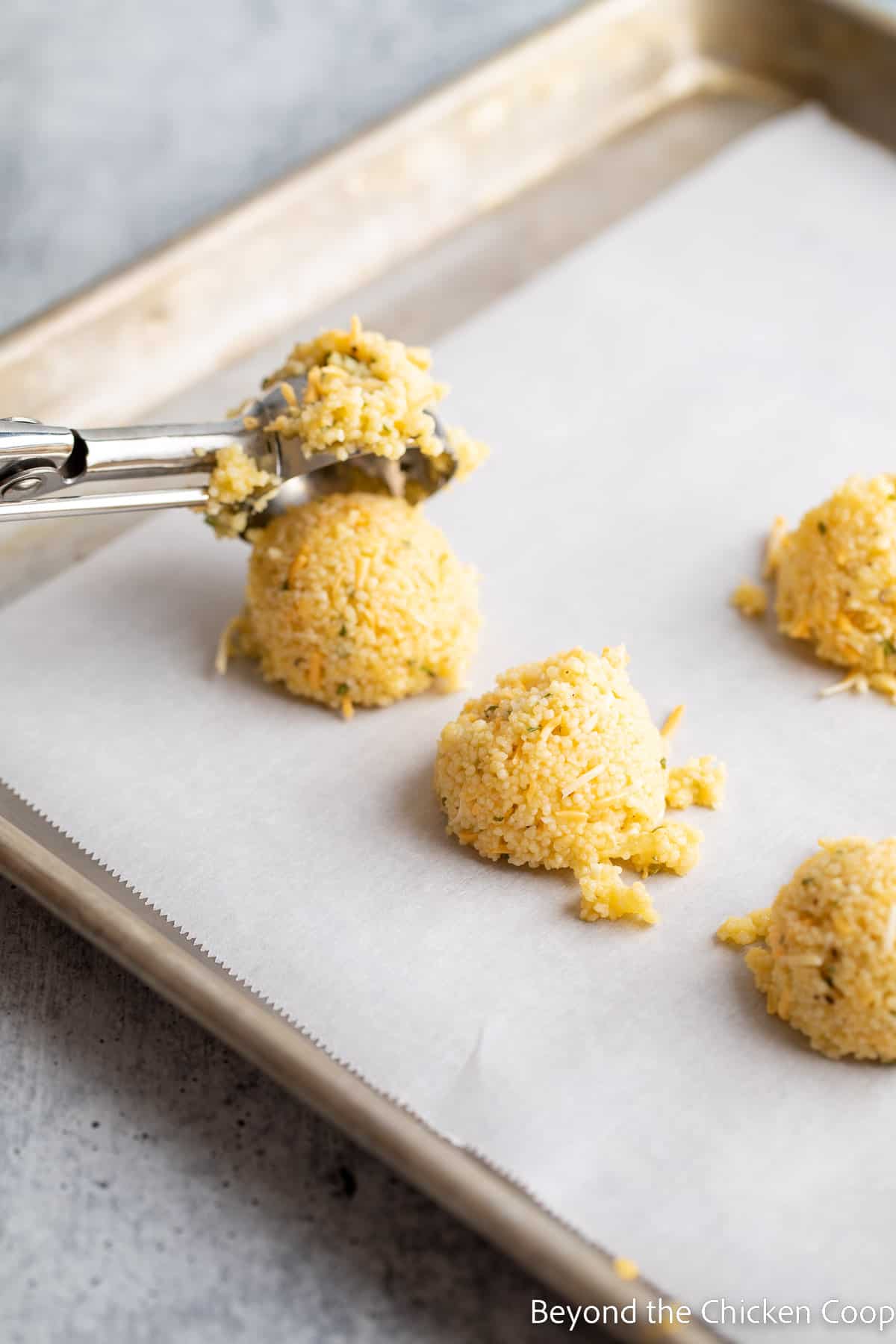 Dropping mounds of couscous onto a baking sheet.