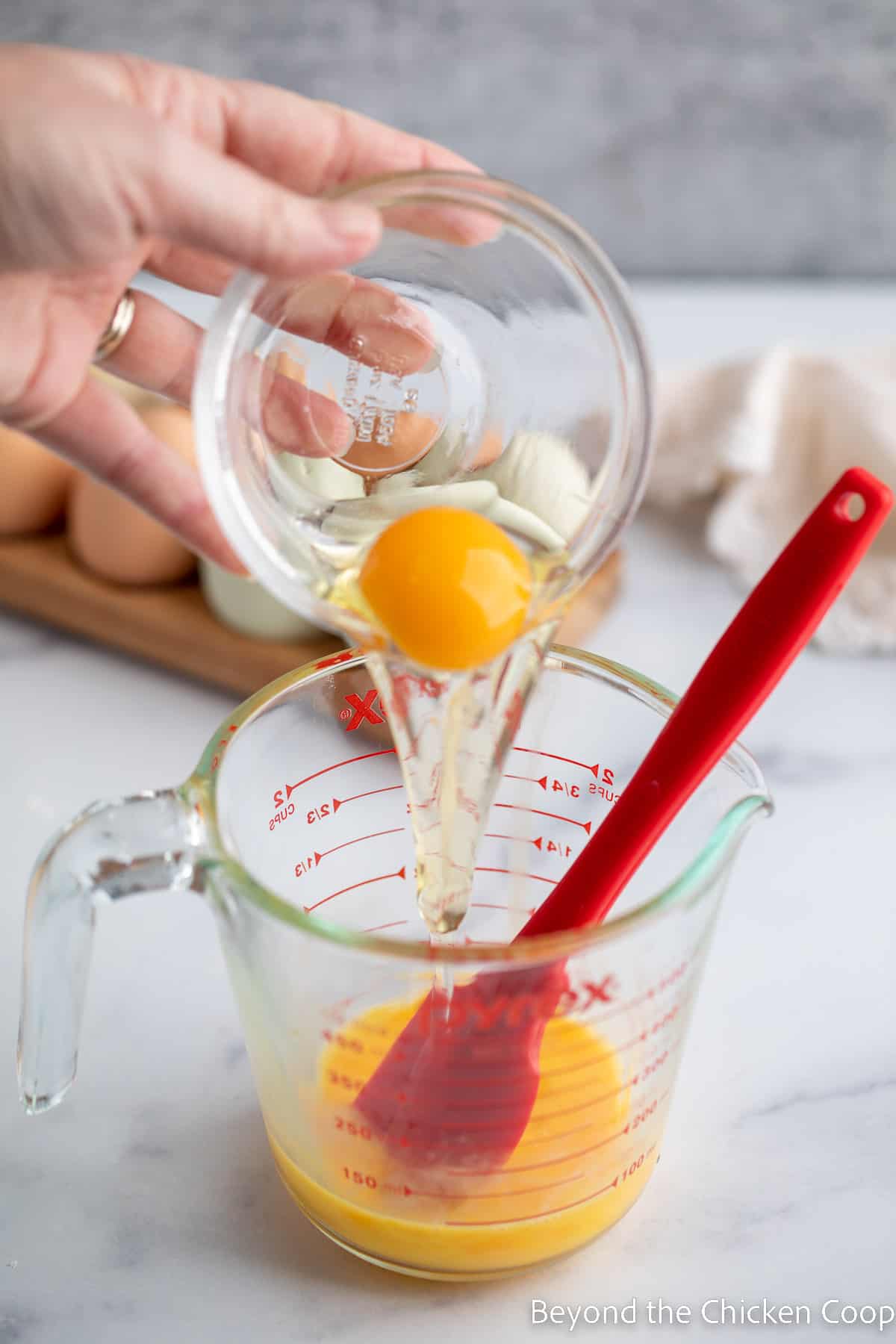 Adding an egg to a glass bowl. 