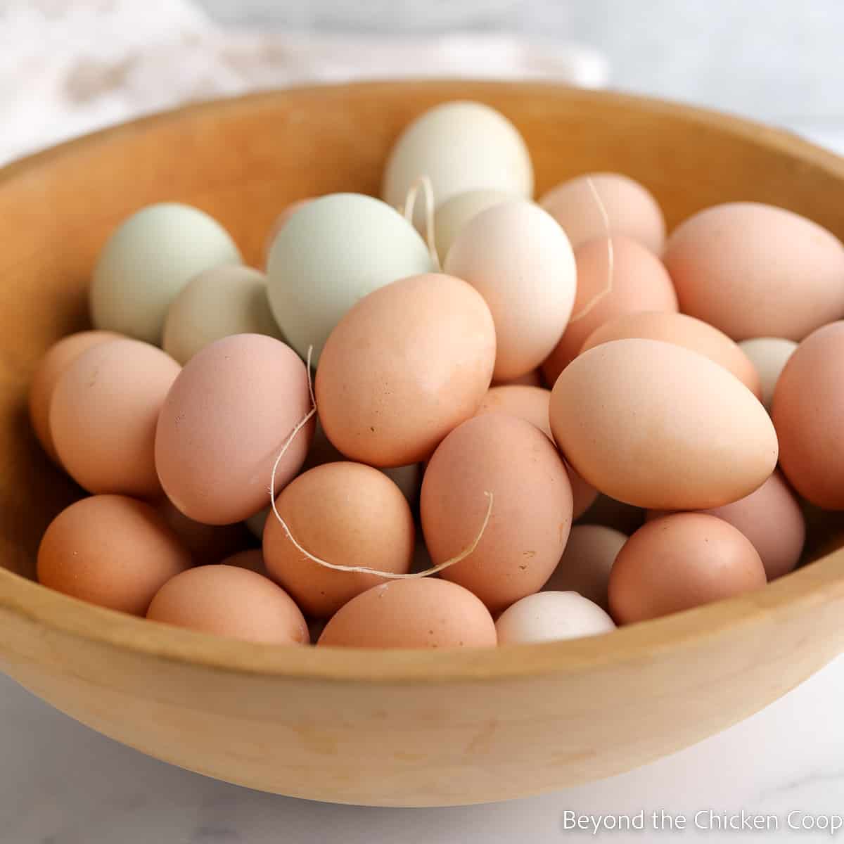 A wooden bowl filled with fresh chicken eggs.
