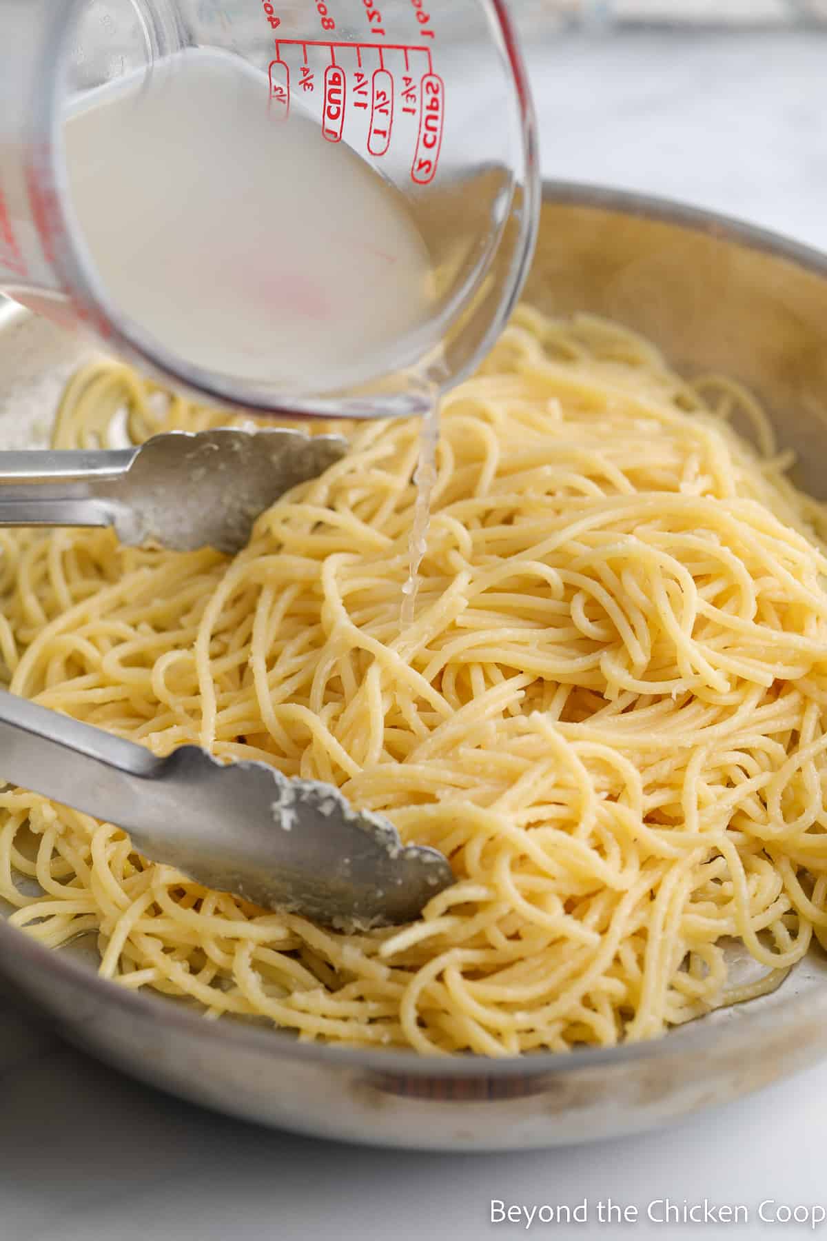 Adding pasta water to spaghetti.