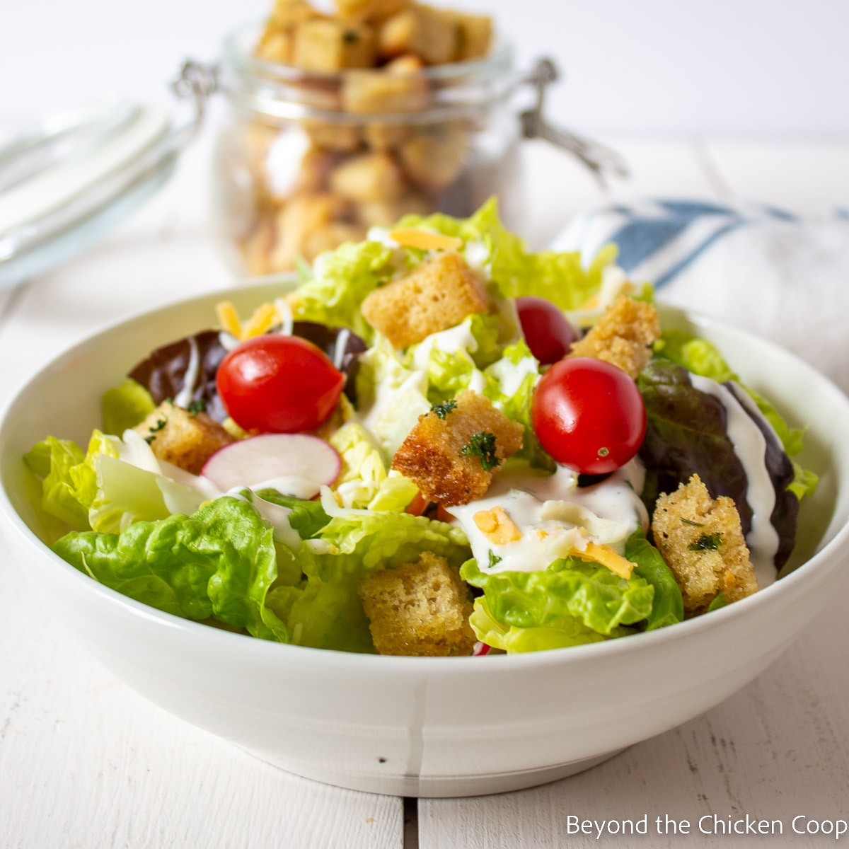 A salad topped with tomatoes and croutons. 