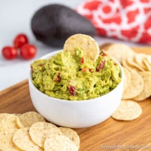 A bowl filled with guacamole with a chip on the top.