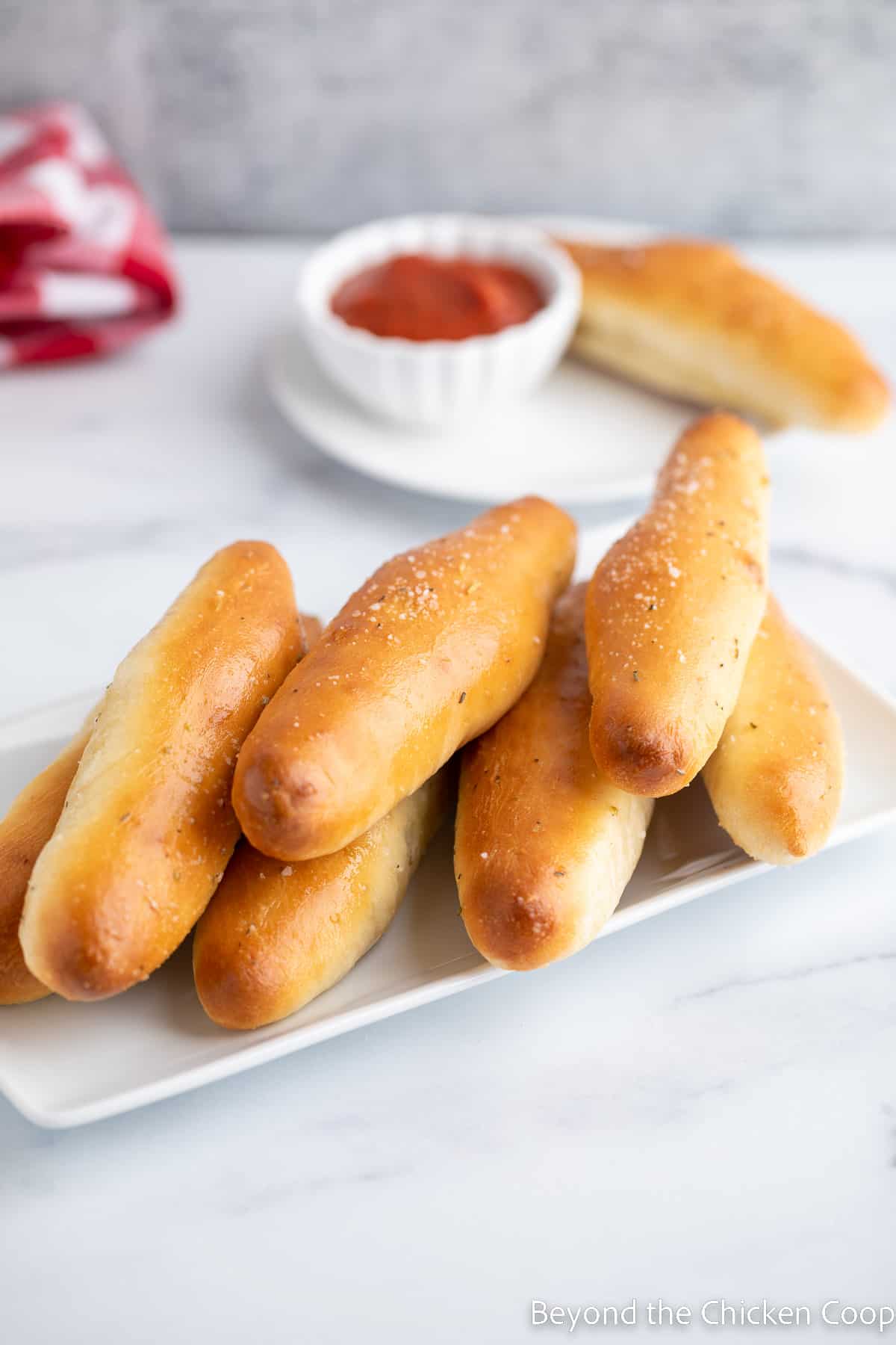 Breadsticks on a white platter. 