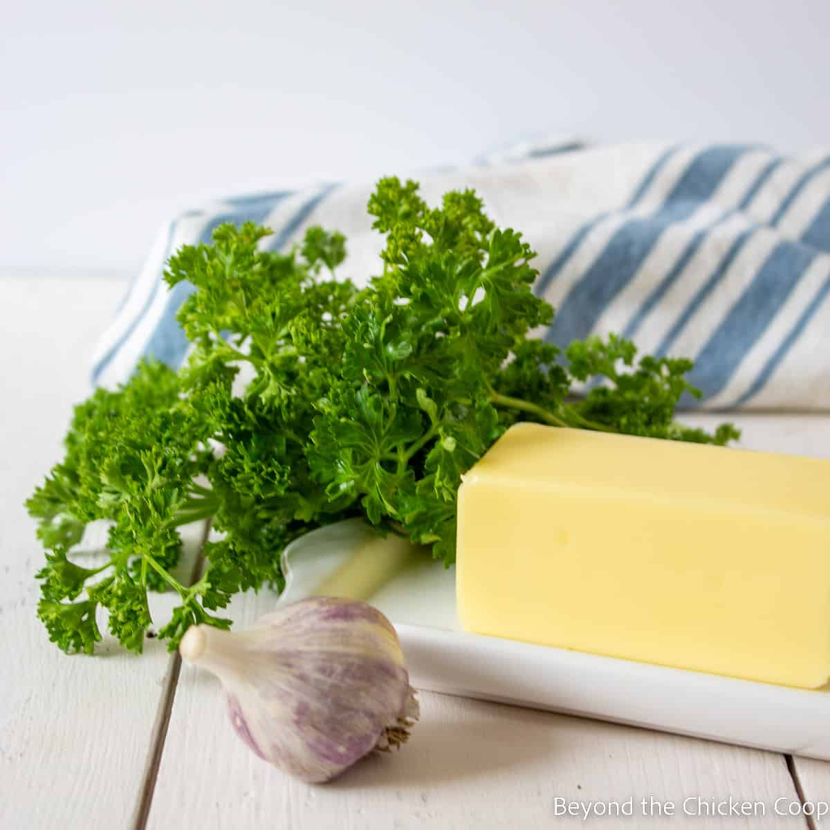 A cube of butter, fresh parsley and a head of garlic. 