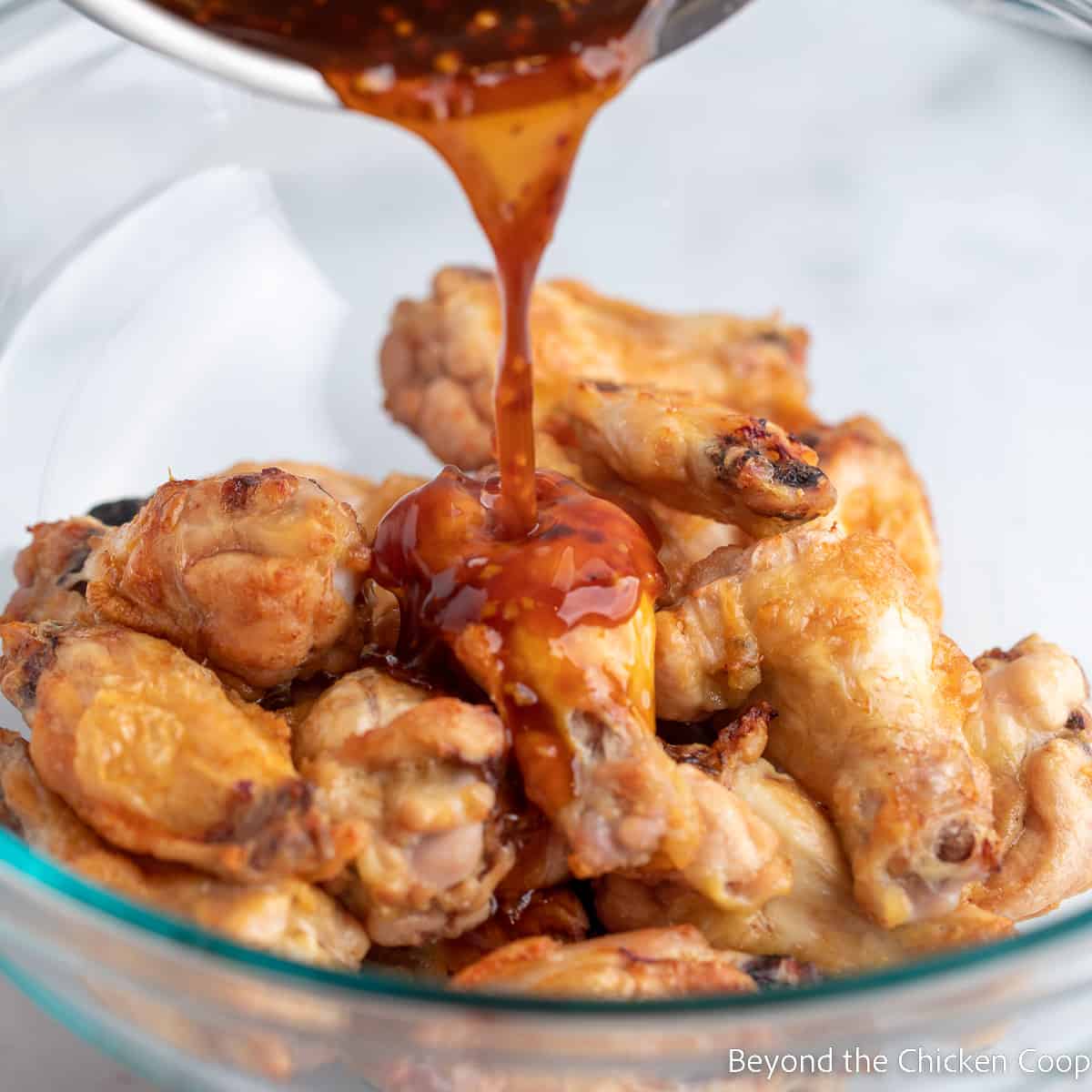 Pouring sauce over baked wings. 