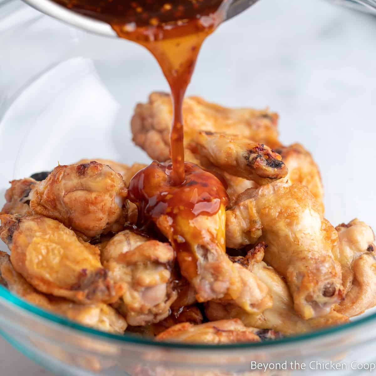 Pouring sauce over baked wings.
