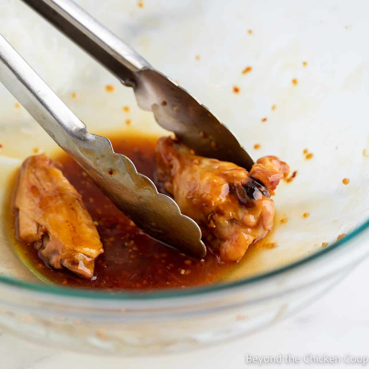 Chicken wings in a bowl with sauce. 