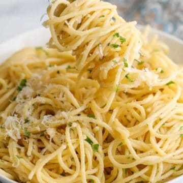 Pasta twirled around a fork and in a large white bowl.