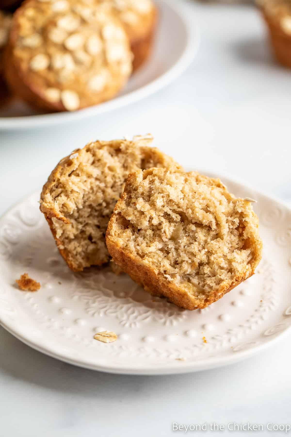 A white plate with a muffin cut in half on the plate. 