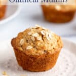 A muffin with oats on a small white embossed plate.