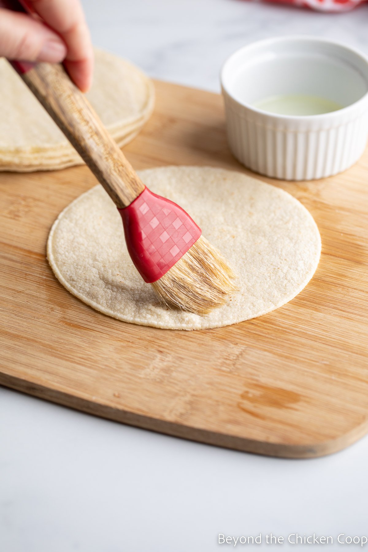 Brushing oil on the top of tortillas.