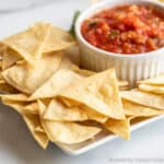 Tortilla chips and a bowl of salsa on a platter.