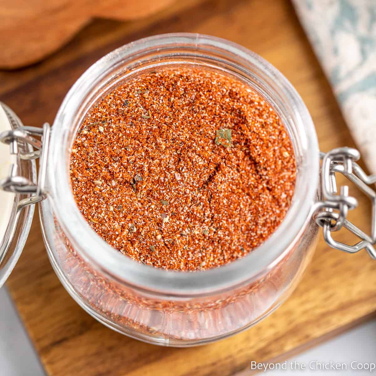 A glass jar filled with a red spice blend.