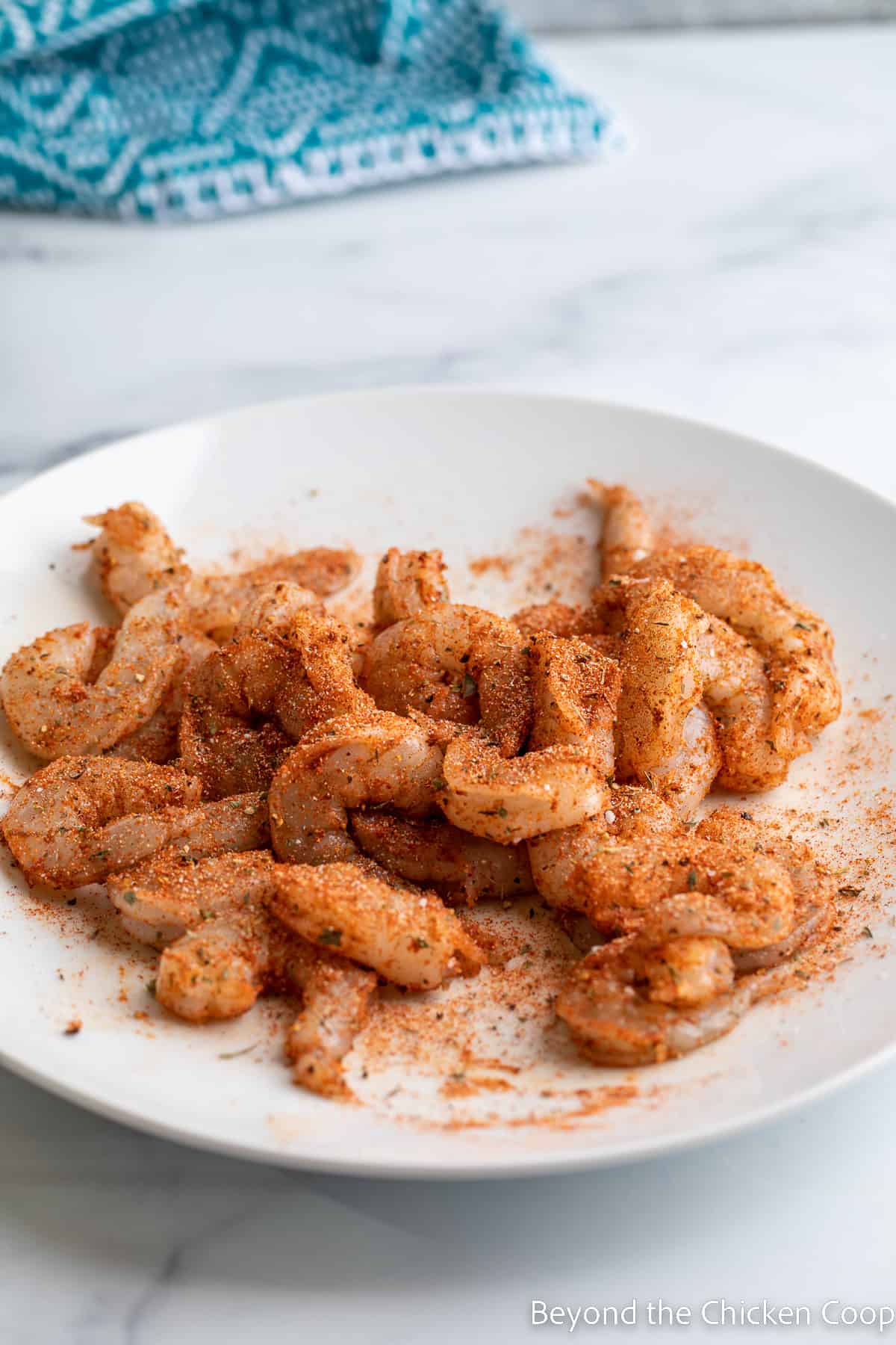 A plate of uncooked seasoned shrimp. 