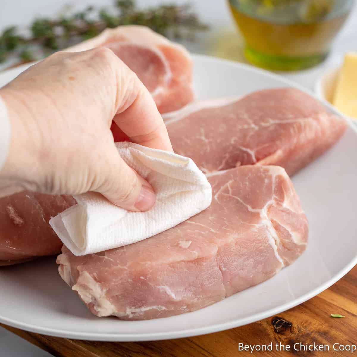 Patting pork chops with a paper towel. 