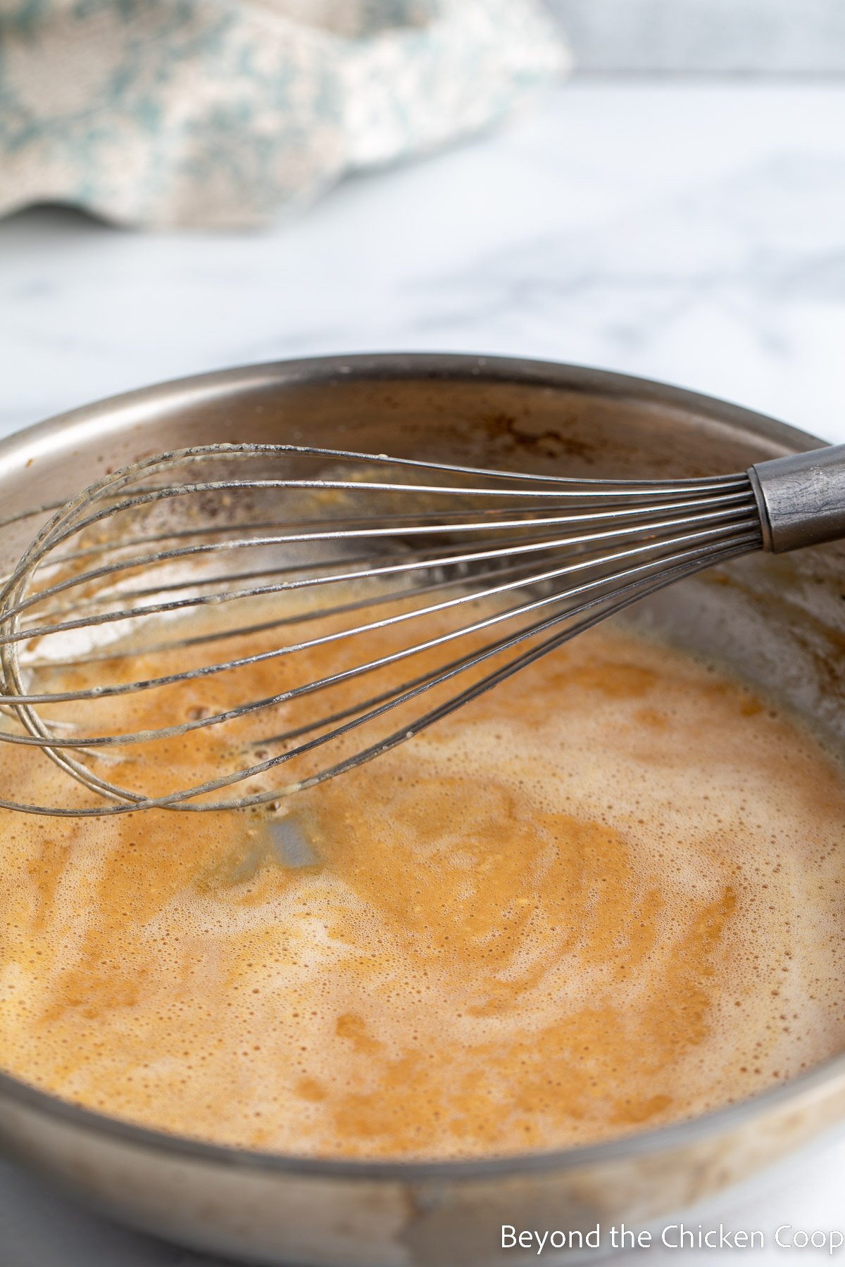 Whisking a brown sauce together in a pan.