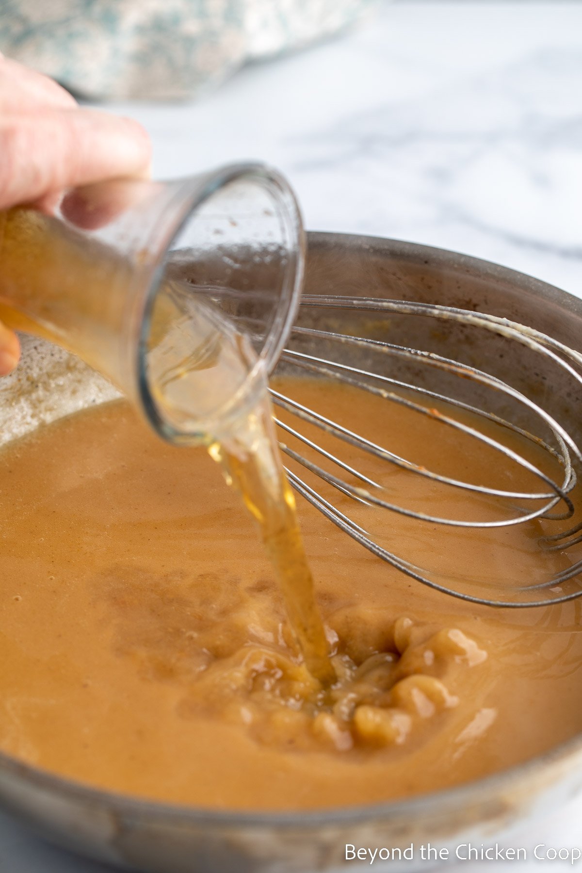 Pouring beef broth into a pan to make gravy. 