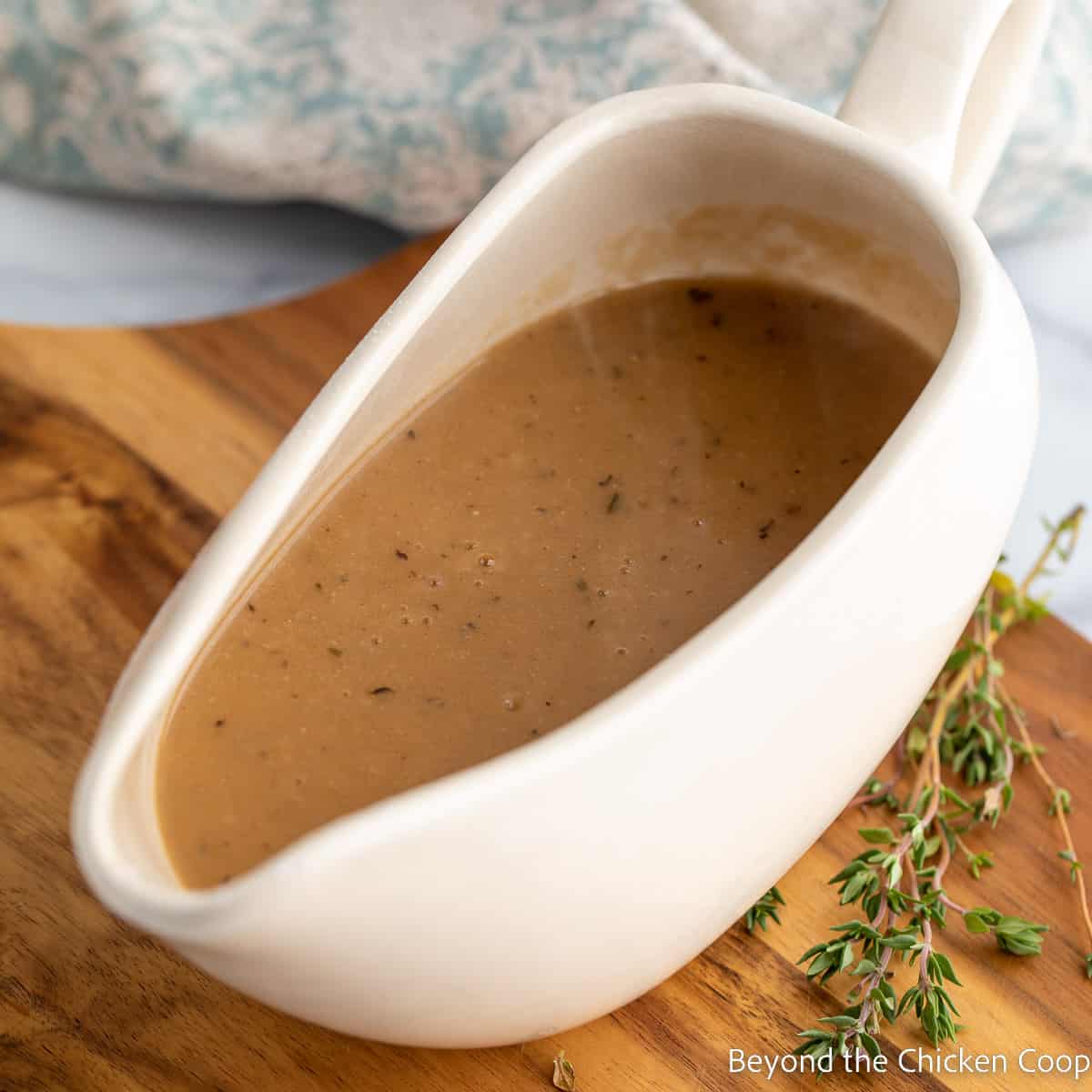 A gravy boat filled with a brown gravy.