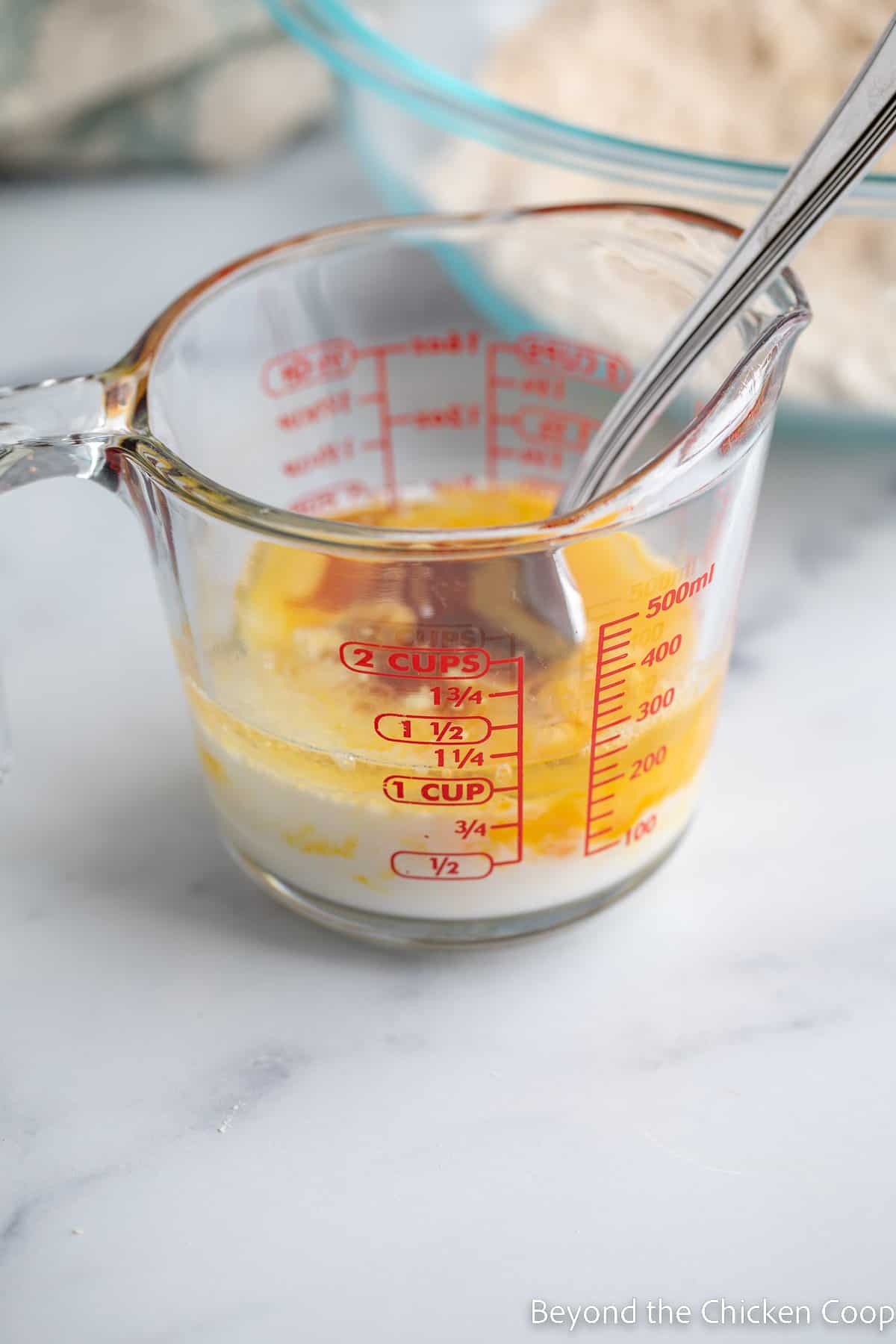 Mixing eggs with milk in a glass measuring cup. 