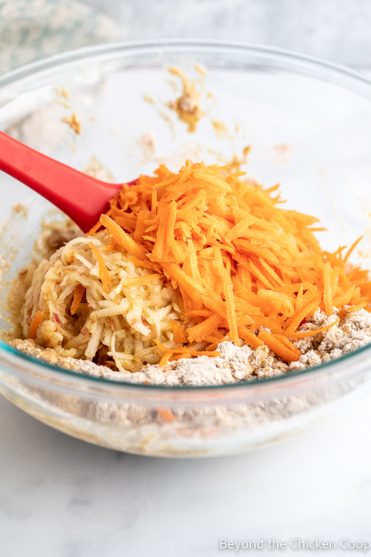 Adding shredded carrots and apples to batter. 