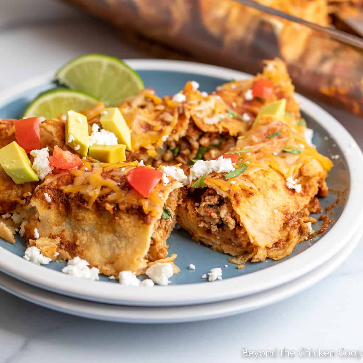 Enchiladas cut in half on a blue plate.