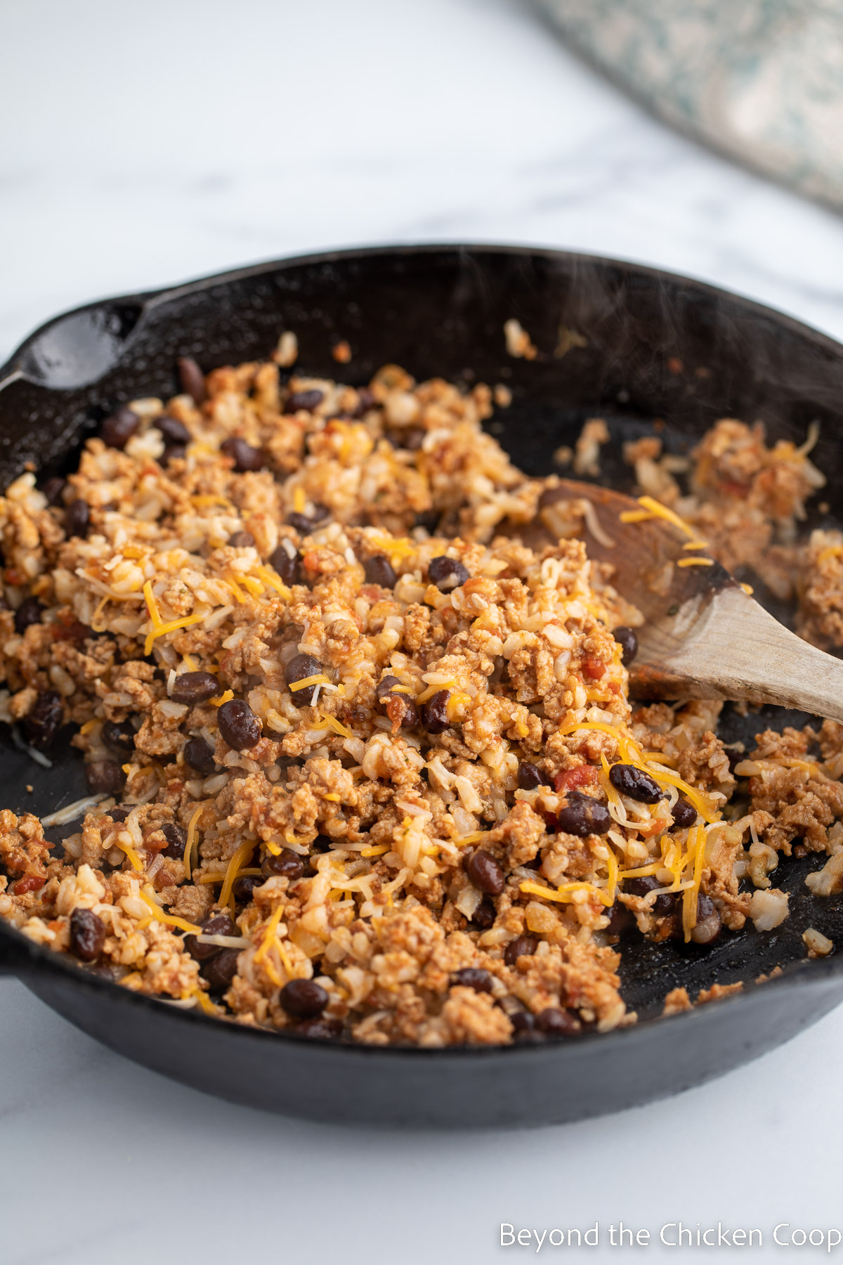 Cooked turkey burger with rice, beans and cheese.