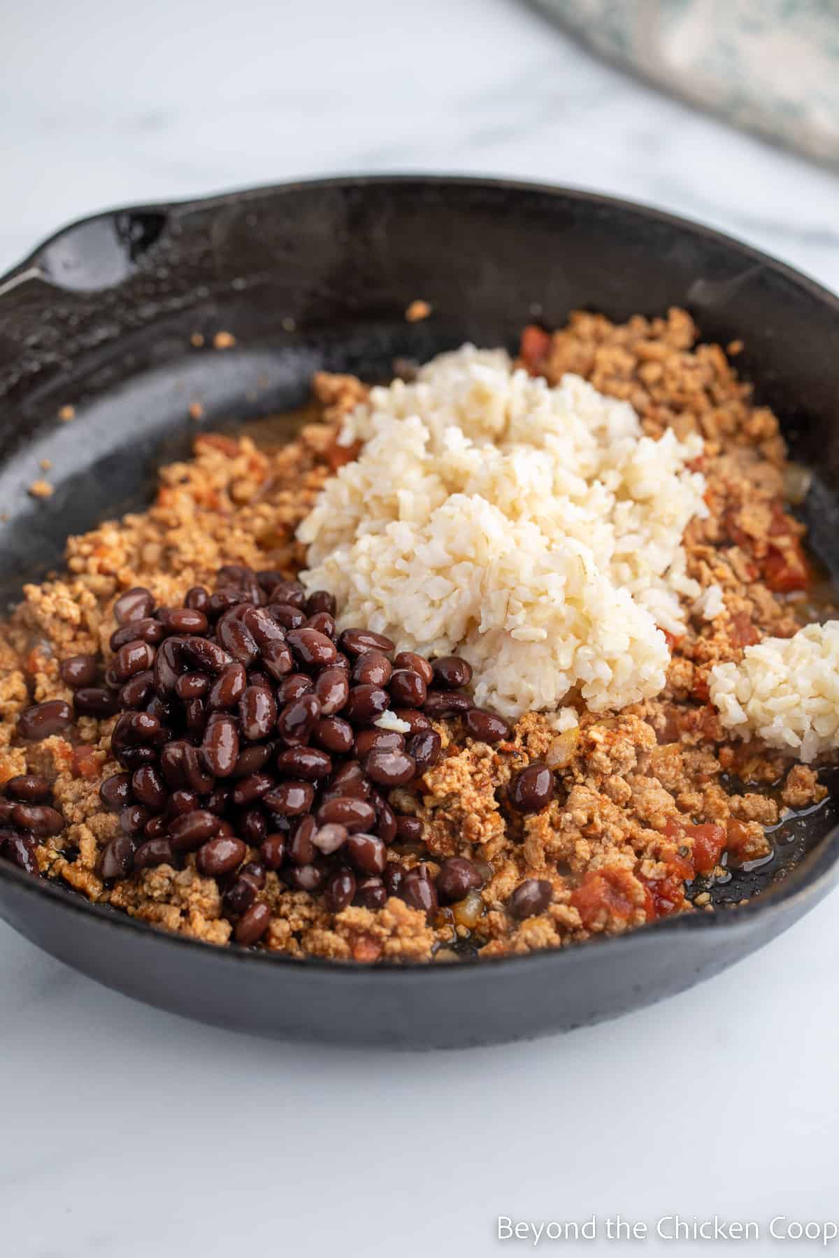 Adding beans and rice to a burger mixture. 