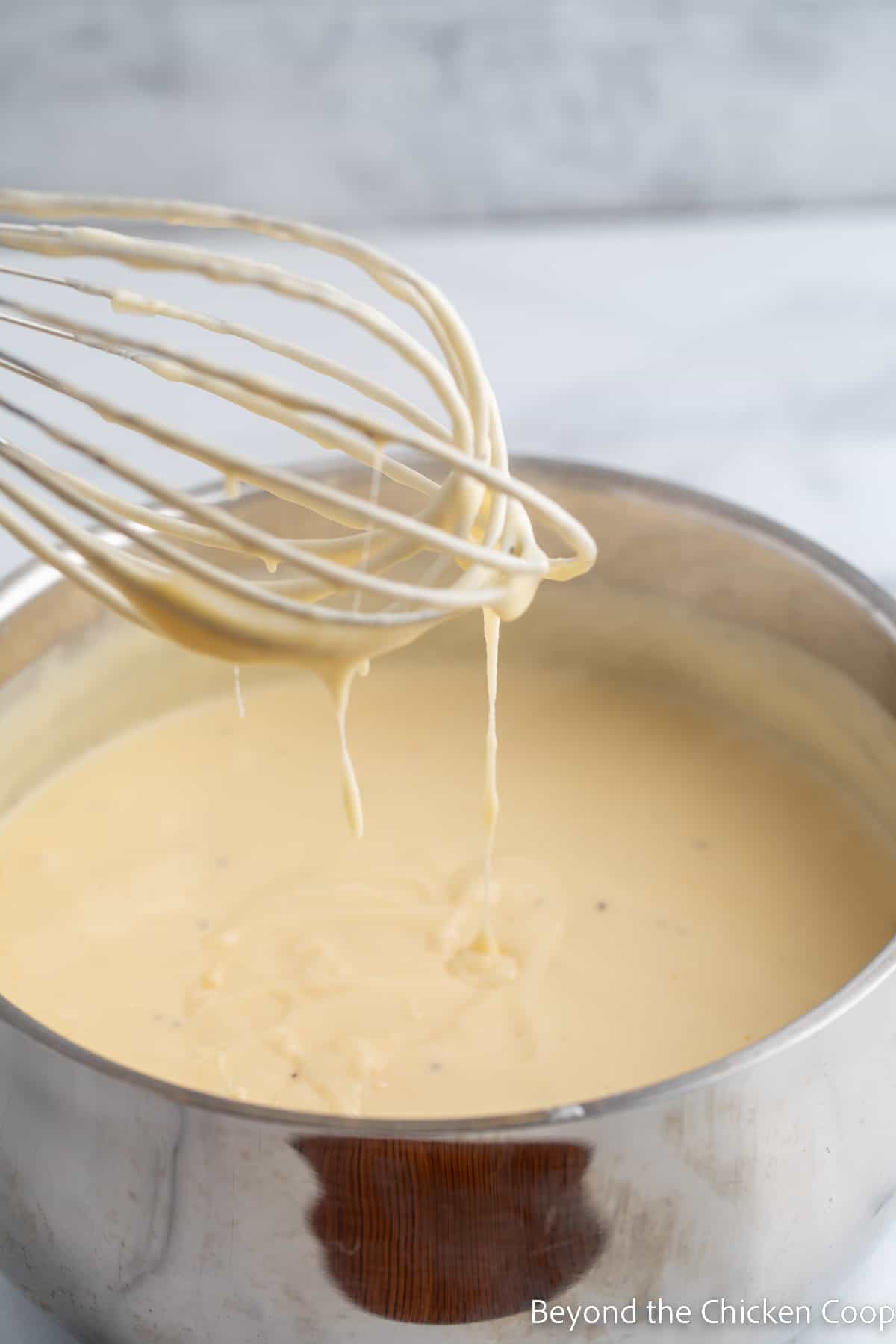 A whisk with a cheese sauce. 