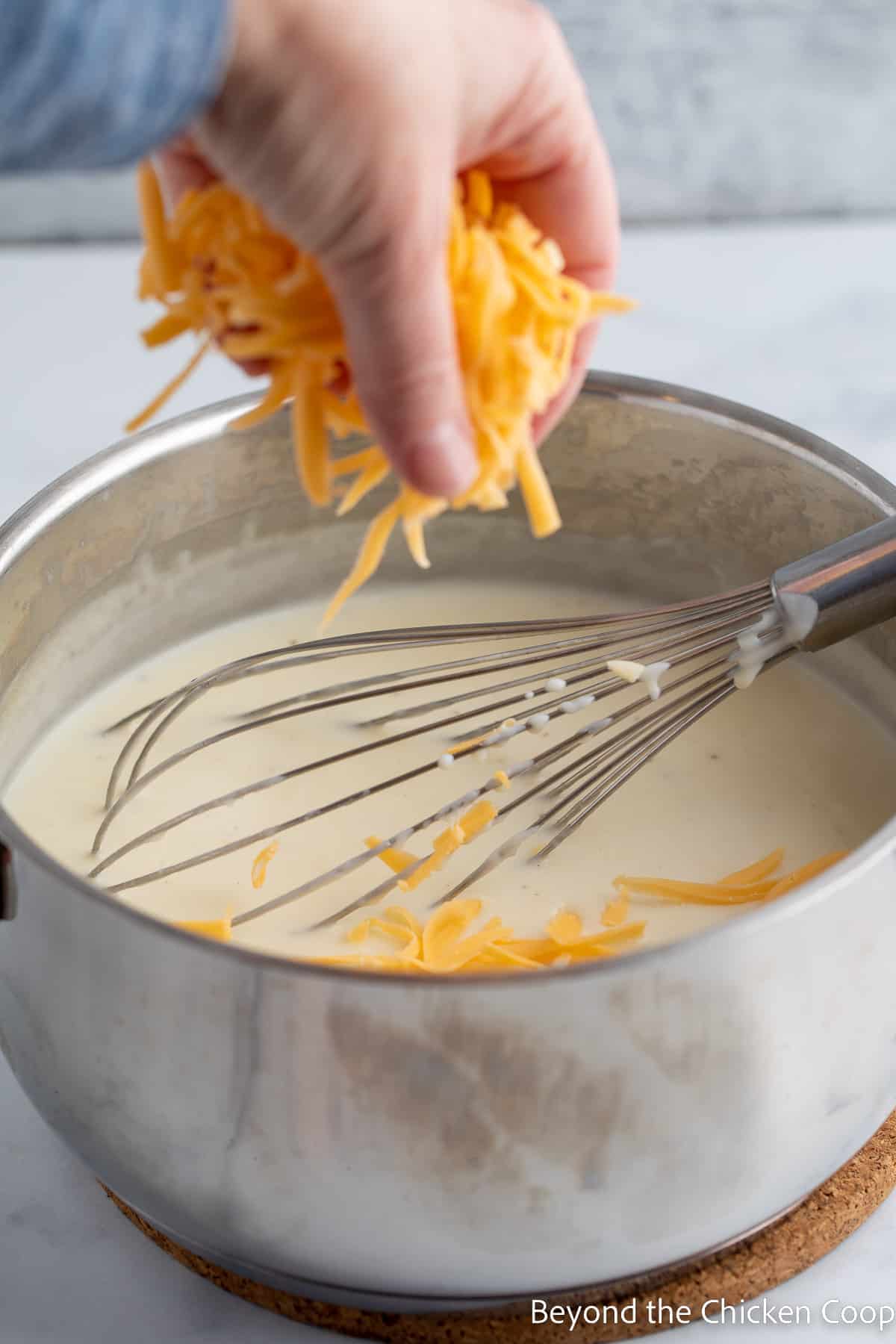 Sprinkling shredded cheese into a saucepan. 