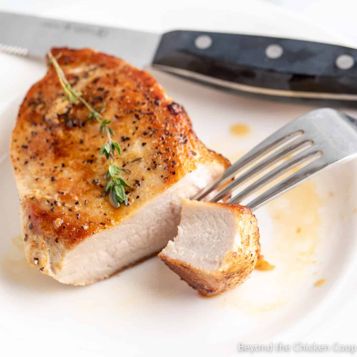 A sliced pork chop with a bite of meat on a fork. 